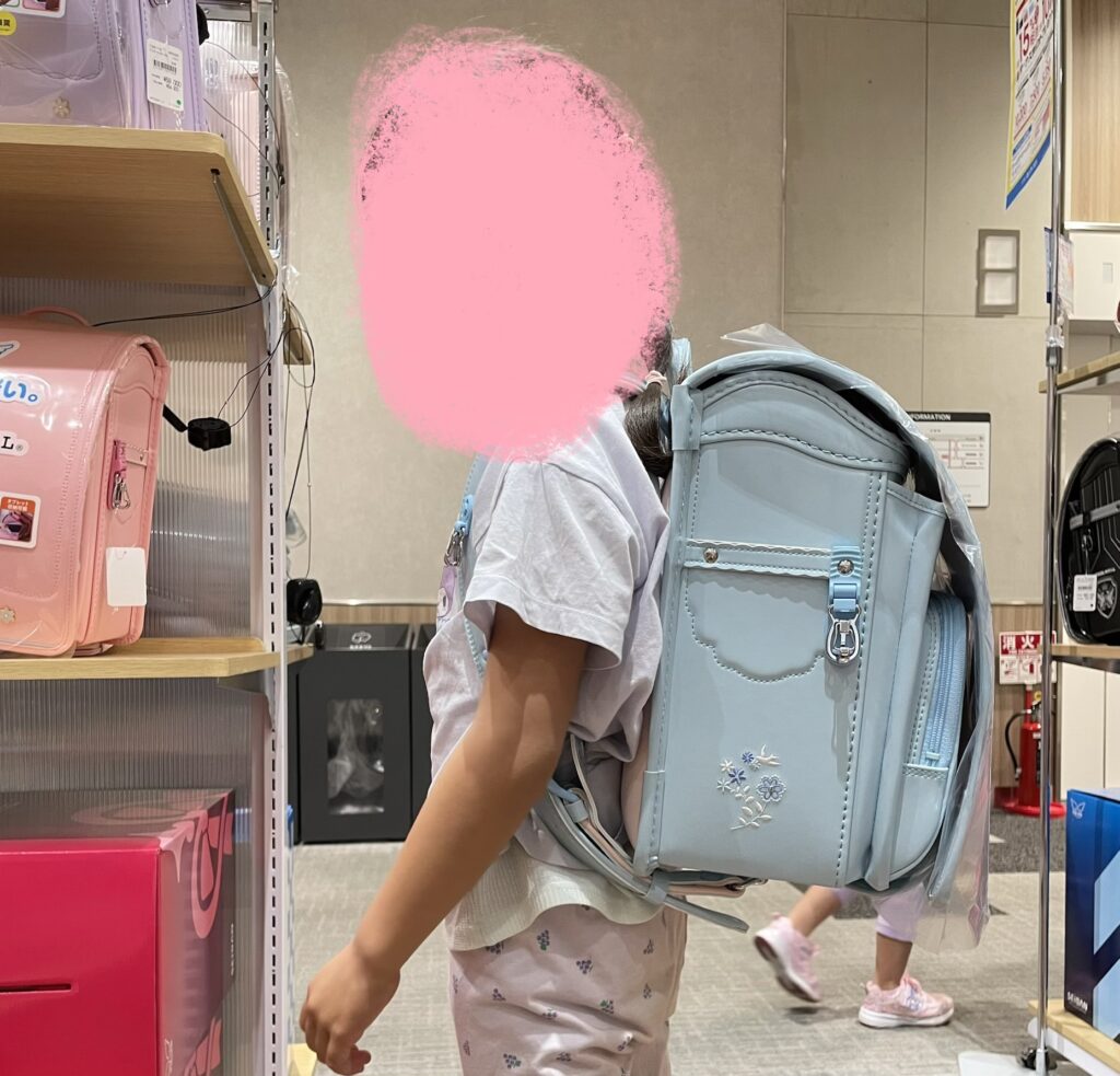 水色のランドセルを背負ってみる娘